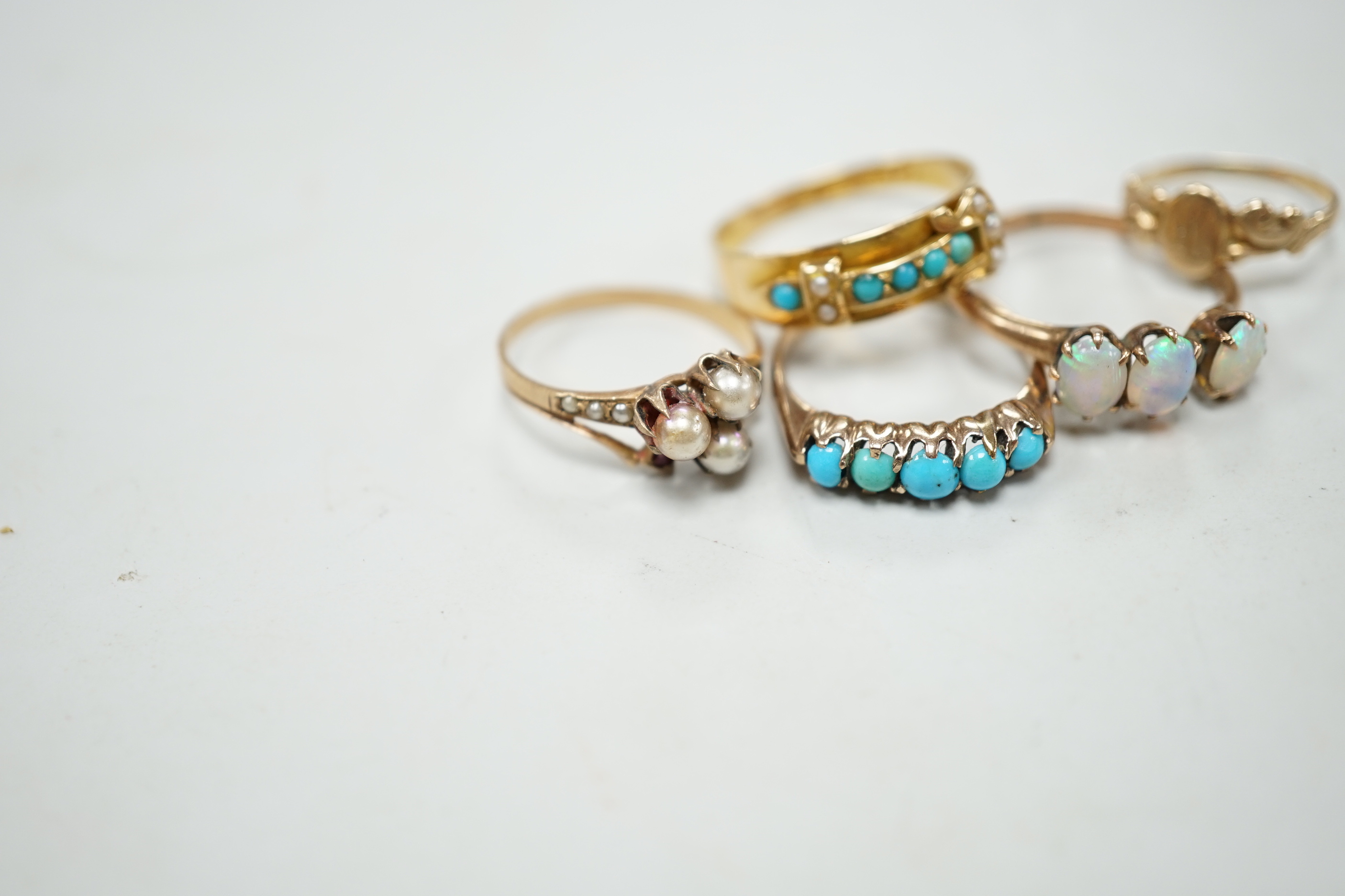 A late Victorian 18ct gold, turquoise and seed pearl set buckle ring, size P and four other yellow metal rings including gem set, gross weight 9 grams (a.f.).
